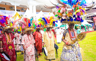 Vibrant scene from the Onitsha Ofala Festival 2024 showcasing colourful Igbo fashion and cultural performances, highlighting themes of courage and self-reliance.