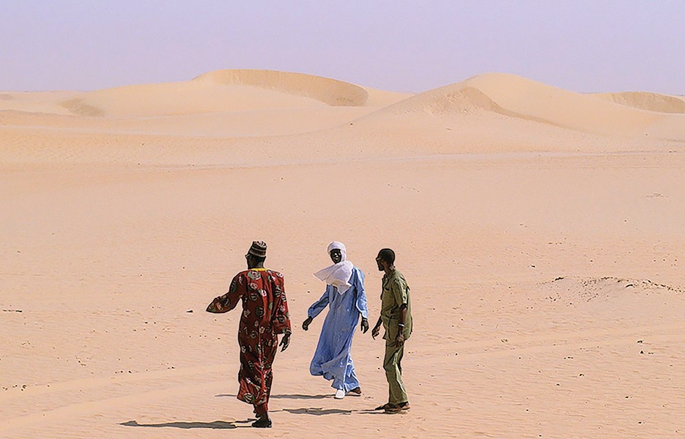 A picture of travellers walking through a northern Nigerian desert village. 