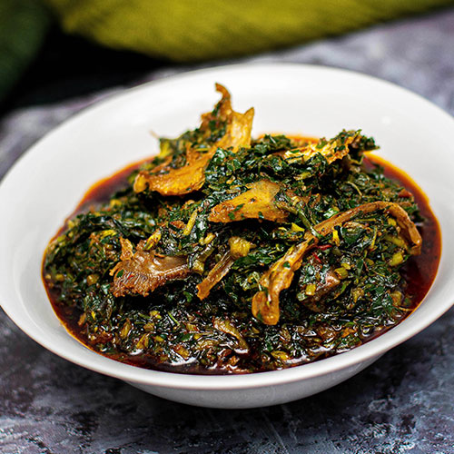 A picture of Afang soup prepared with afang leaves, stock fish, and periwinkle, a well-loved local dish to try in Akwa Ibom during the holidays.