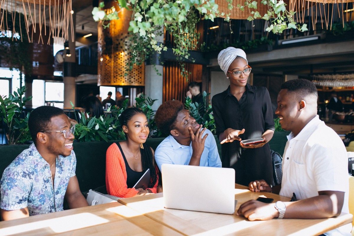 Group of young Nigerians having a conversation in a restaurant.
