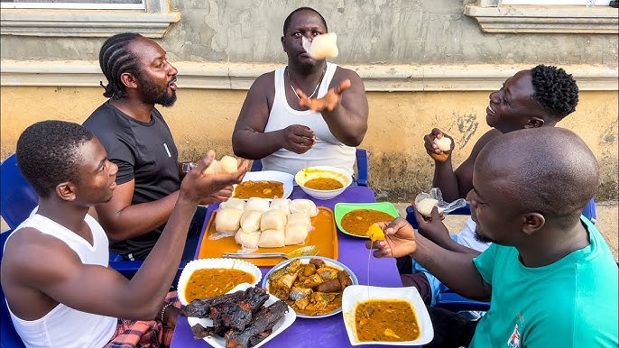 Happy Nigerian men sharing a meal on a round table.
