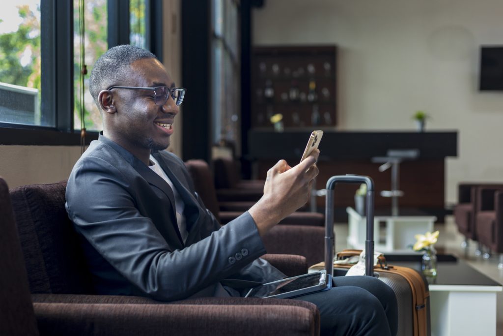  Nigerian man waiting in an office while on his phone, one way to Avoid Travel Scams and Fake Agents in Nigeria