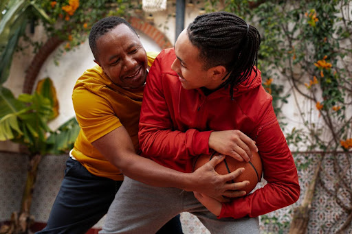 Nigerian men playing basketball outdoors.
