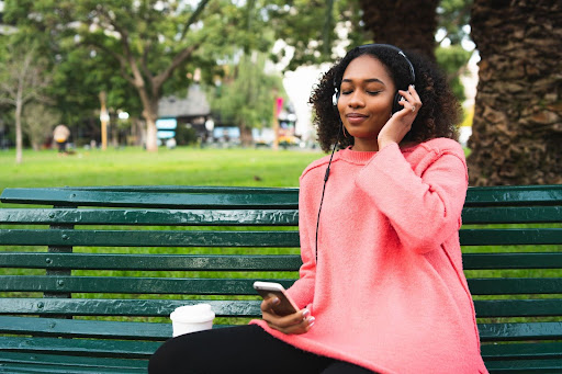 Nigerian lady listening to music while chilling in a park.
