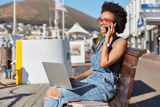 A woman is happily working in a tourist area, which illustrates one of the benefits of strong air connectivity.